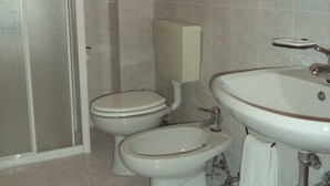 Baño con dos inodoros, un lavamanos y una ducha.