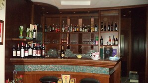 Zona de bar con estantes de botellas de licor, vasos y un llamativo salpicadero de azulejos.