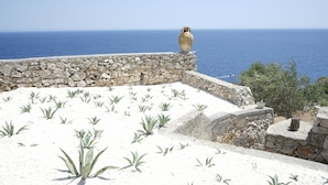 A stone wall with a vase on top and agave plants in the foreground. - Hotel Piccolo Mondo (Castro)