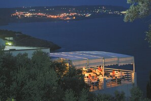 A coastal view with a building featuring a covered outdoor area with seating. - Hotel Piccolo Mondo (Castro)