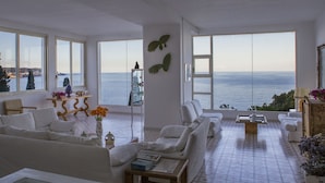 A spacious living room with a large view of the sea, white furniture, and a tiled floor. - Hotel Piccolo Mondo (Castro)