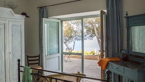 A room with a view of the sea, a dining area with a table and chairs, and a bed with a headboard. - Hotel Piccolo Mondo (Castro)
