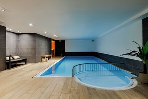 A modern indoor swimming pool with a wooden deck, a bench, and a potted plant. - Hotel Saint Sauveur by WP Hotels (Blankenberge)