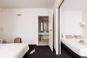 A hotel room with two beds, a bathroom, and a suitcase on the floor. - Hotel Saint Sauveur by WP Hotels (Blankenberge)