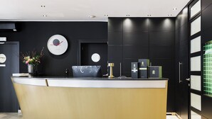 A reception desk with a curved design, a clock, and a vase with flowers.