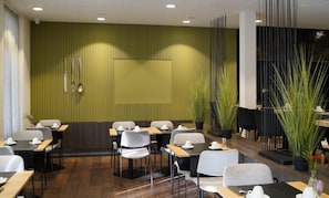 A modern dining area with tables and chairs, a green accent wall, and potted plants. - Hotel Saint Sauveur by WP Hotels (Blankenberge)