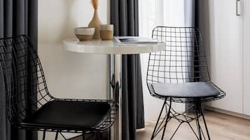 Une pièce moderne avec une table ronde, deux chaises, un vase contenant des plantes séchées et un meuble blanc.