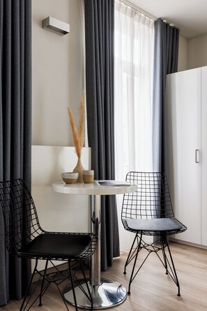 A modern room with a round table, two chairs, a vase with dried plants, and a white cabinet. - Hotel Saint Sauveur by WP Hotels (Blankenberge)