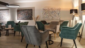 A modern lounge area with multiple seating options, including chairs and sofas, and artwork on the walls.