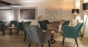 Et moderne loungeområde med flere siddepladser, herunder stole og sofaer, samt kunst på væggene.