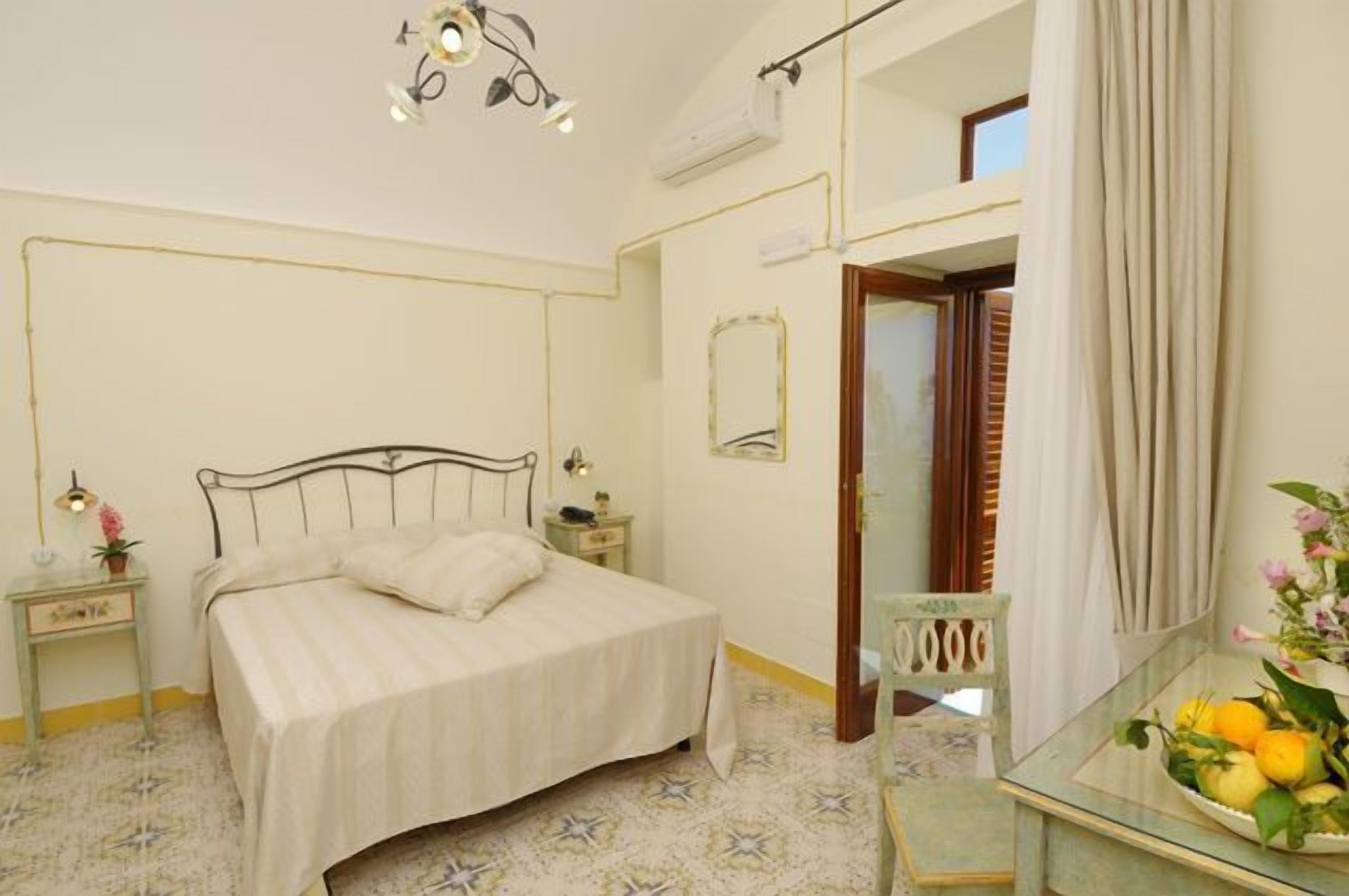 A bedroom with a bed, bedside tables, a mirror, and a small table with fruit.