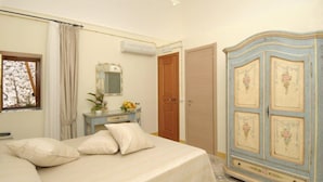 Een slaapkamer met een bed, een dressoir, een spiegel en een deur.