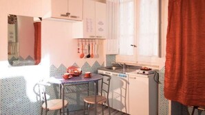 Une cuisine de taille réduite avec une petite table à manger, des chaises et les appareils électroménagers de base.