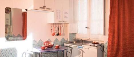 A compact kitchen with a small dining table, chairs, and basic appliances.