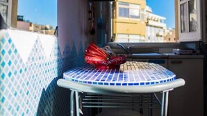 Un petit coin cuisine avec un mur recouvert de carreaux, un tabouret en métal et un objet rouge posé sur le comptoir.