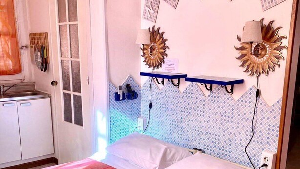 Une chambre d’hôtel avec un lit, une petite kitchenette et des œuvres d’art décoratives au mur.