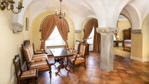 A dining room with a high arched ceiling, a chandelier, and a large table surrounded by upholstered chairs. - Palac Paulinum (Jelenia Gora)