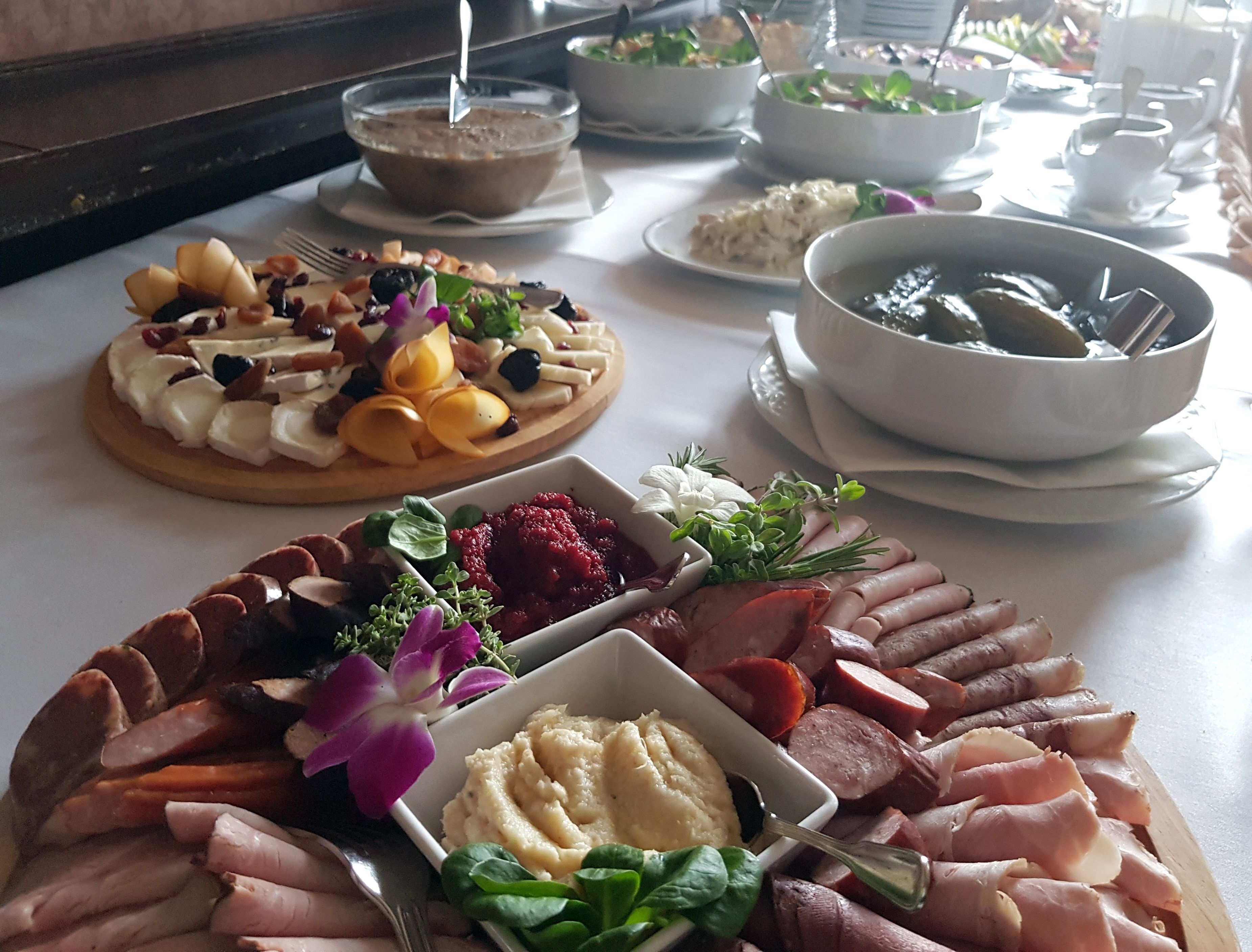 Una mesa de buffet con diversos platos, incluyendo una tarta de frutas, un bol de sopa y una bandeja de carnes y quesos.