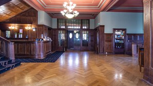 A spacious lobby with a wooden floor, a grand staircase, and a chandelier. - Palac Paulinum (Jelenia Gora)