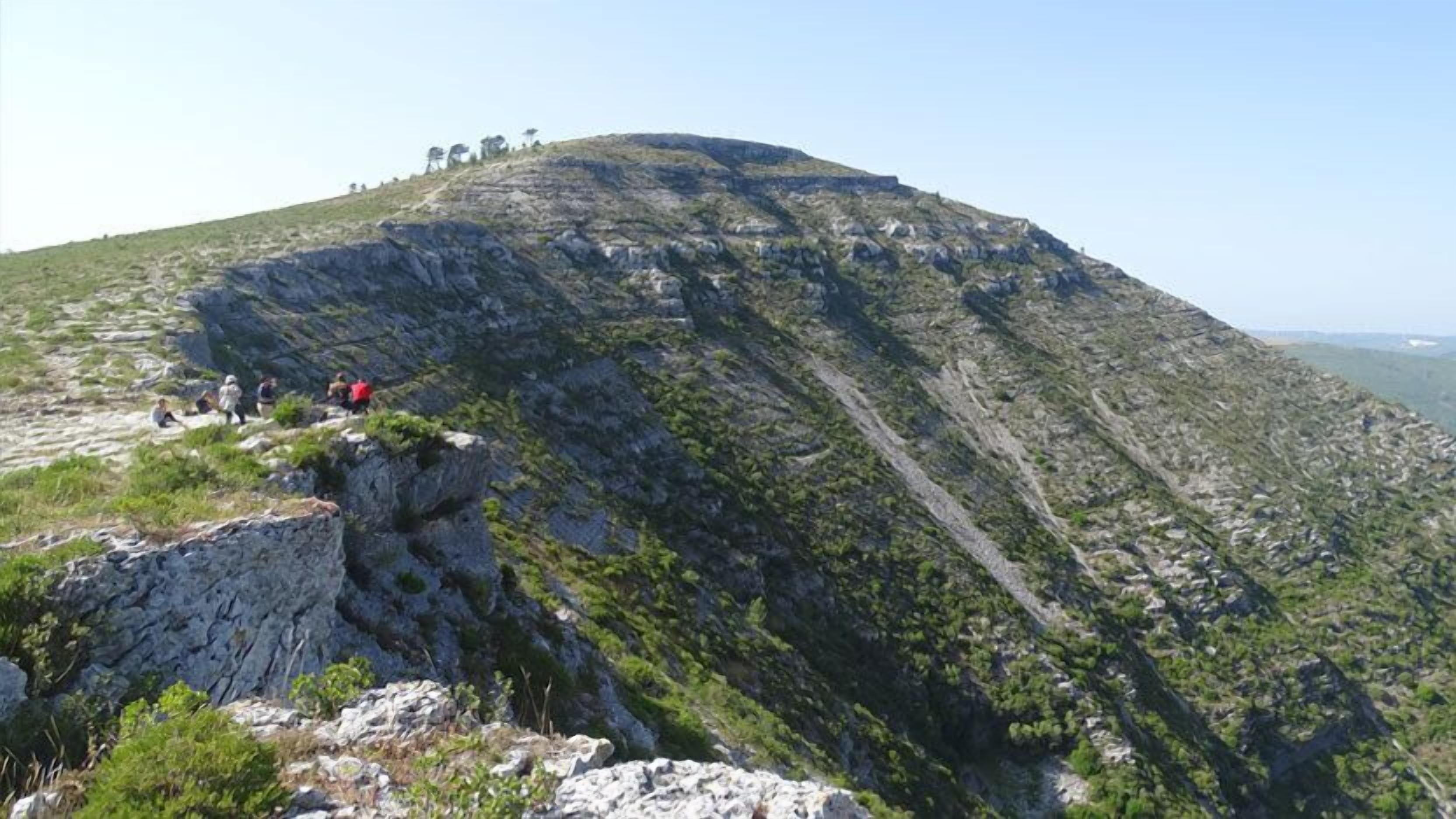 A rocky hillside with a few hikers.
