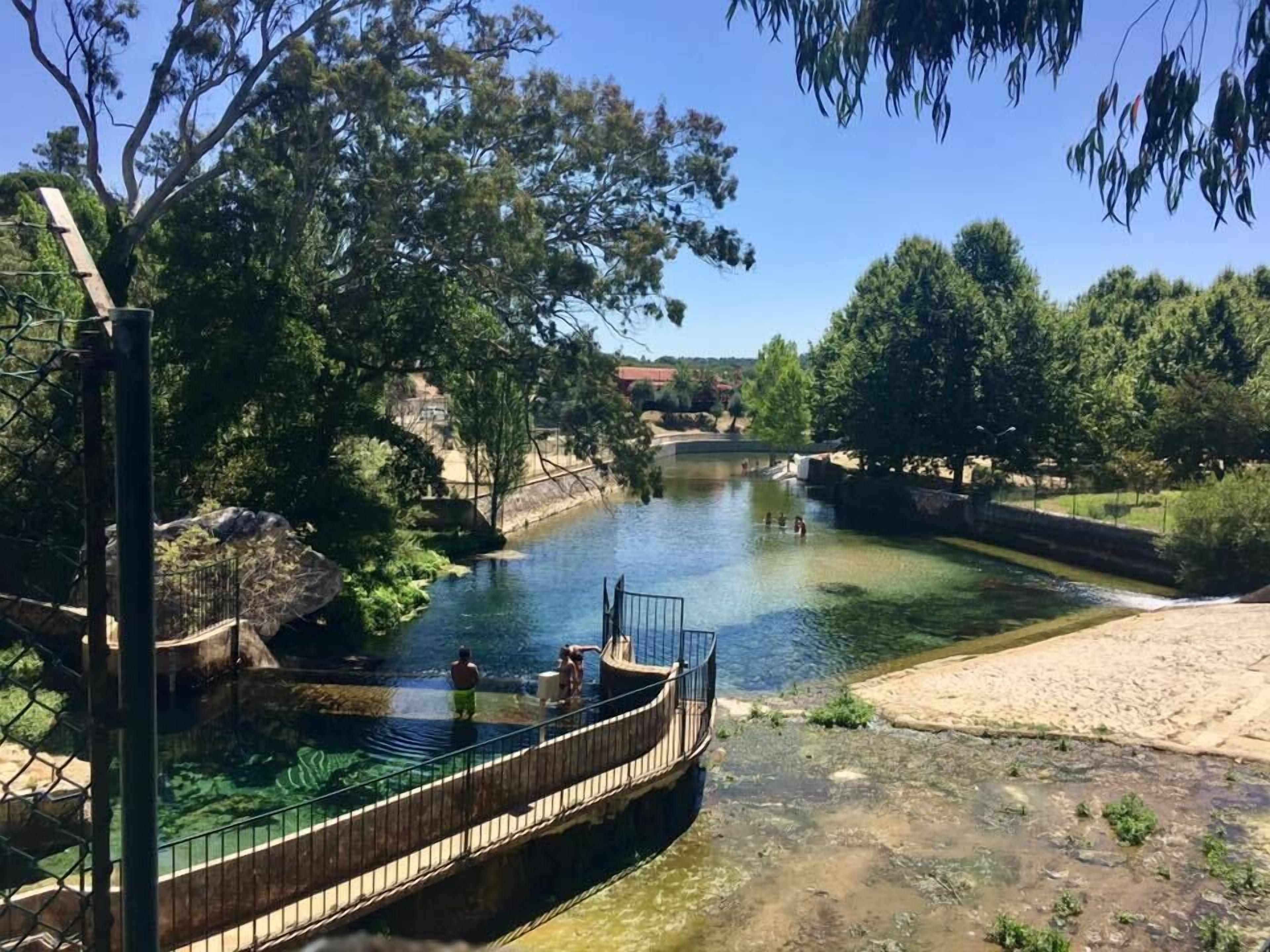 Ein Fluss mit klarem Wasser, umgeben von Bäumen und einem hölzernen Steg.
