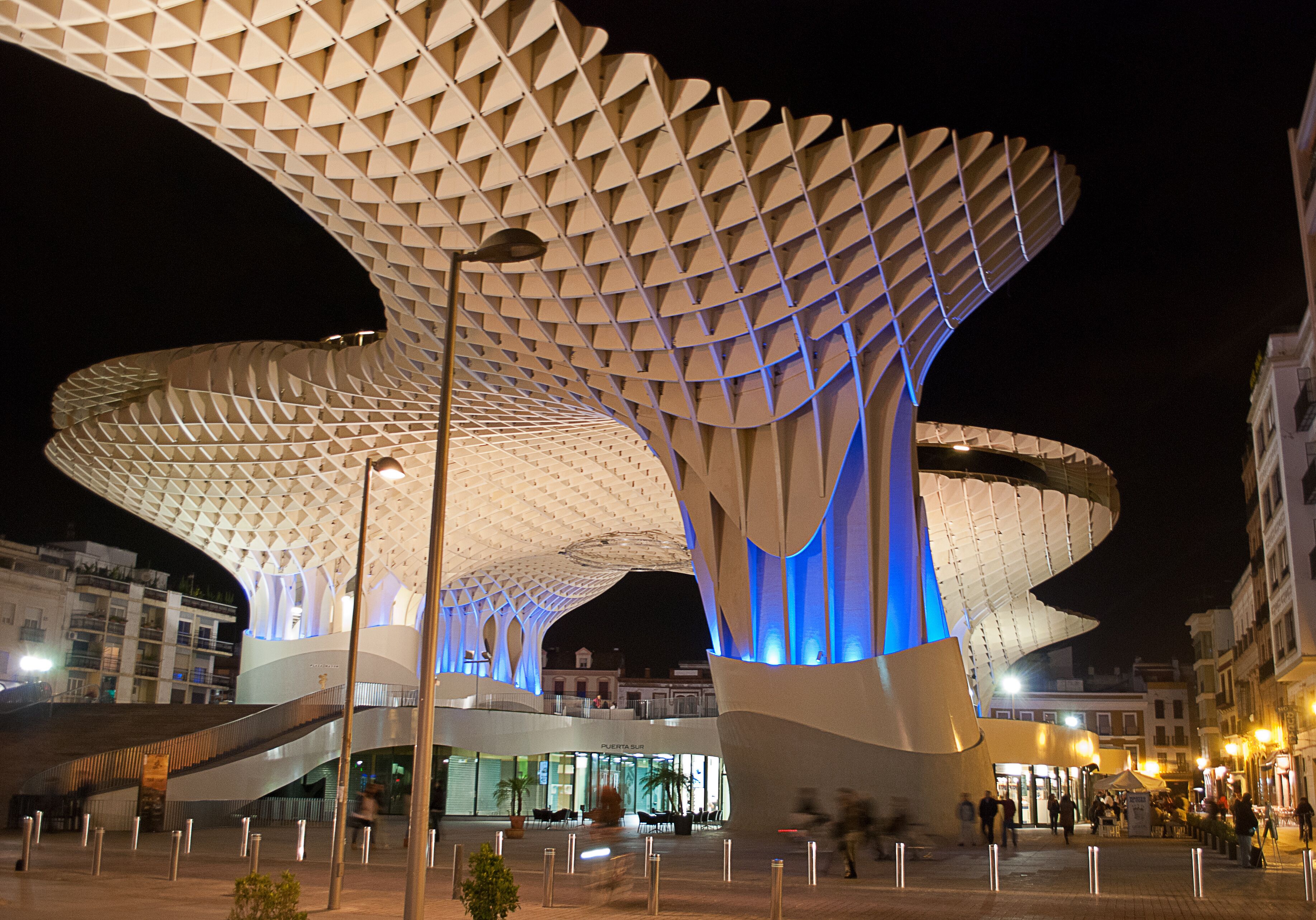 Una estructura arquitectónica moderna con un diseño geométrico único, que destaca por un techo prominente, curvo y similar a una celosía.