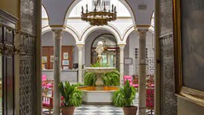 Un pasillo ornamentado con una fuente, columnas y una araña.