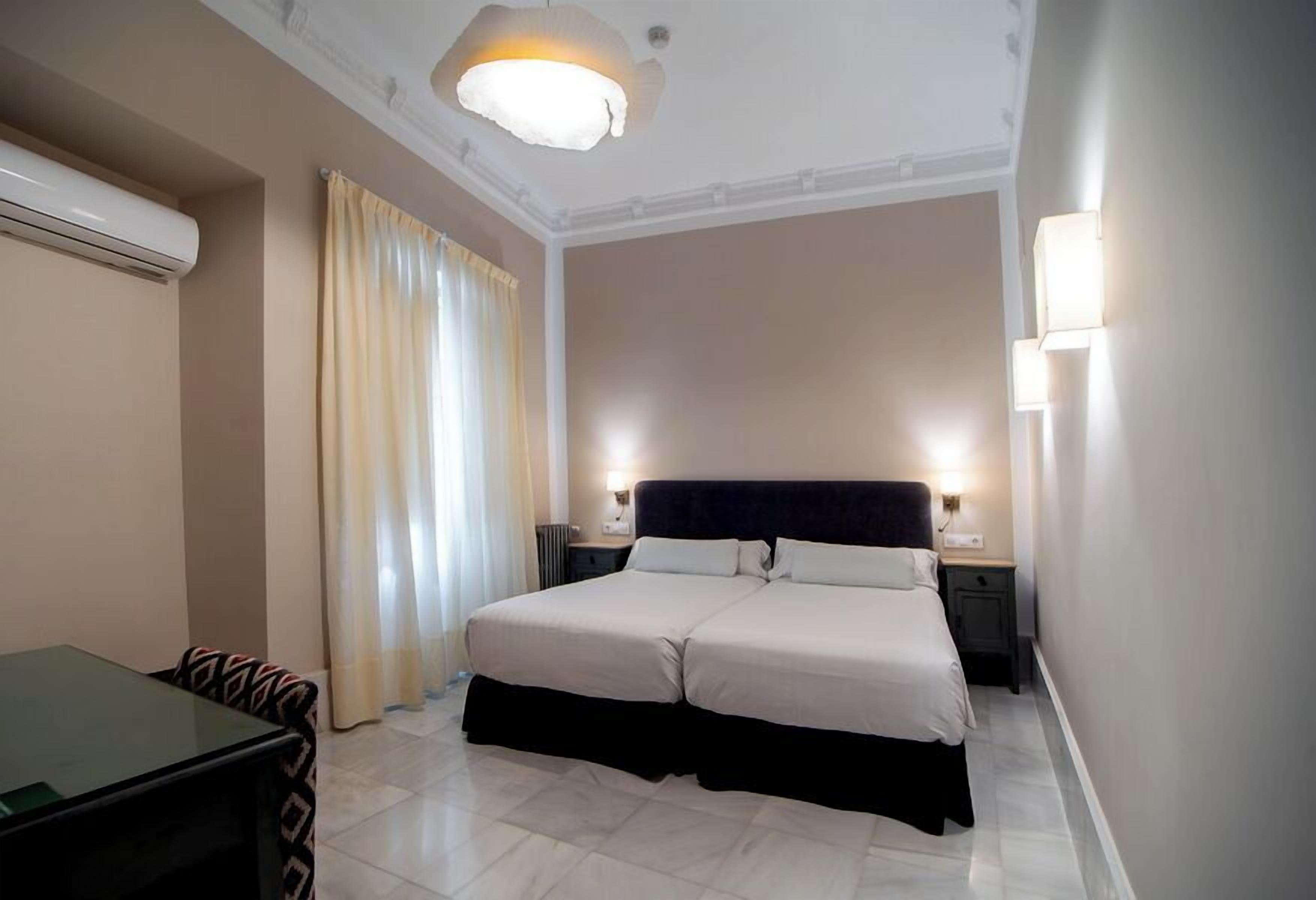 Une chambre d’hôtel avec un lit, des tables de chevet, un bureau et une chaise.