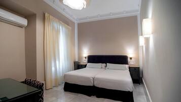 Une chambre d’hôtel avec un lit, des tables de chevet, un bureau et une chaise.