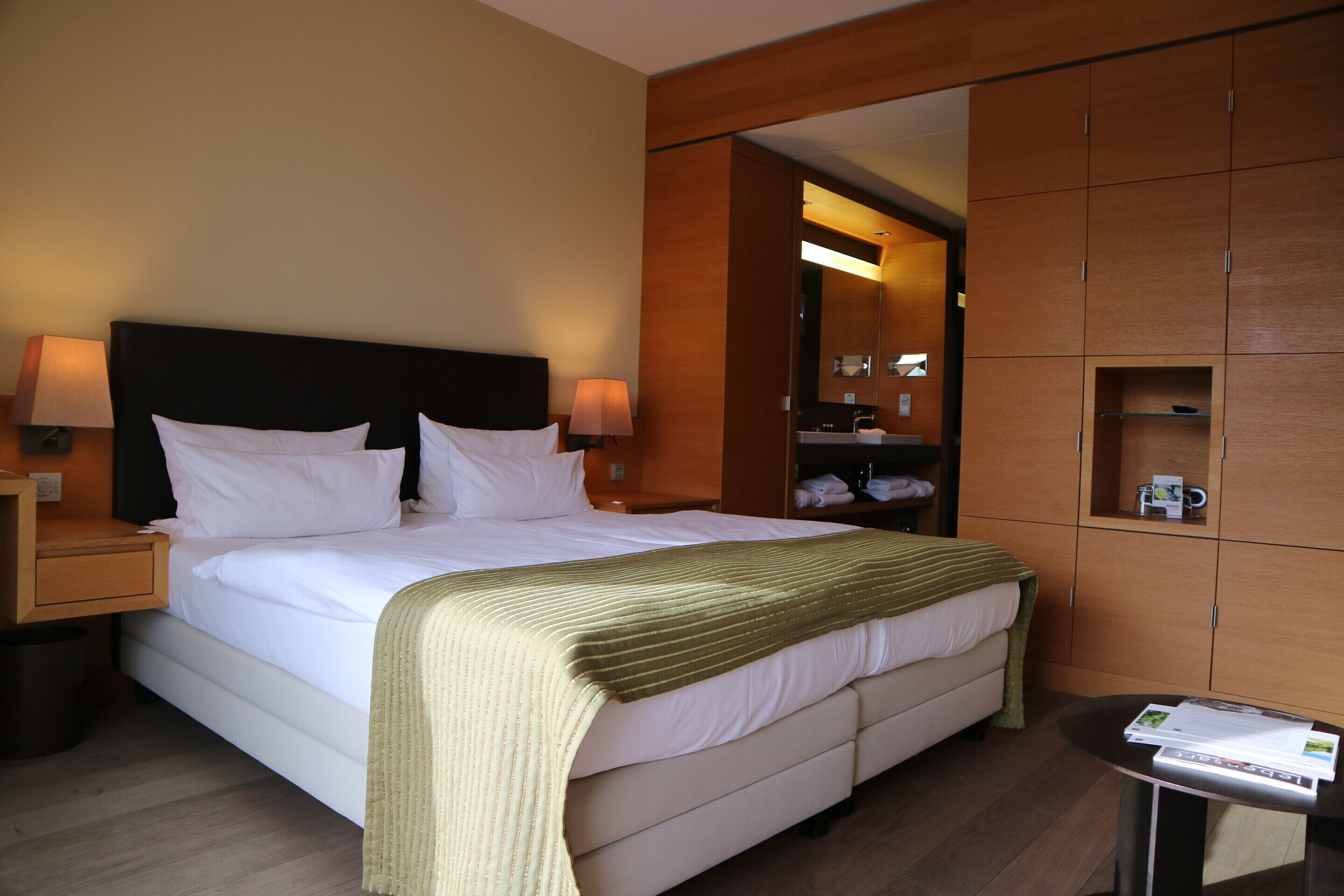 A hotel room with a bed, nightstands, a bedside table, a mirror, and a wardrobe.