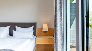 A hotel room with a bed, a nightstand with a lamp, and a view of the outside balcony.