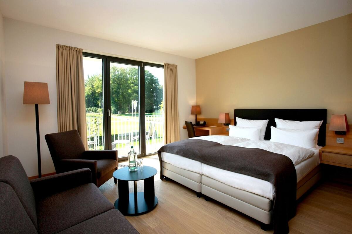 Une chambre d’hôtel avec un lit, une chaise, une petite table et une vue sur l’extérieur.
