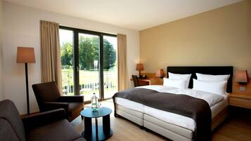Una habitación de hotel con una cama, una silla, una mesita y vistas al exterior.