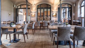 Un vaste espace dédié à la salle à manger, avec des tables et des chaises en bois, des plafonds en arc de cercle et des luminaires fixés aux murs.