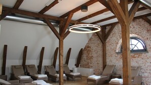 Une salle de spa avec des poutres en bois, des murs en briques et plusieurs fauteuils confortables.