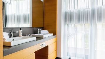 Ein modernes Badezimmer mit zwei Waschbecken, einem großen Spiegel und einer Holzkommode.