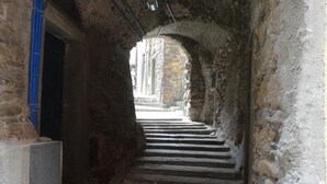 Una stretta scala in pietra che conduce a un ingresso, circondata da muri di pietra rustica.