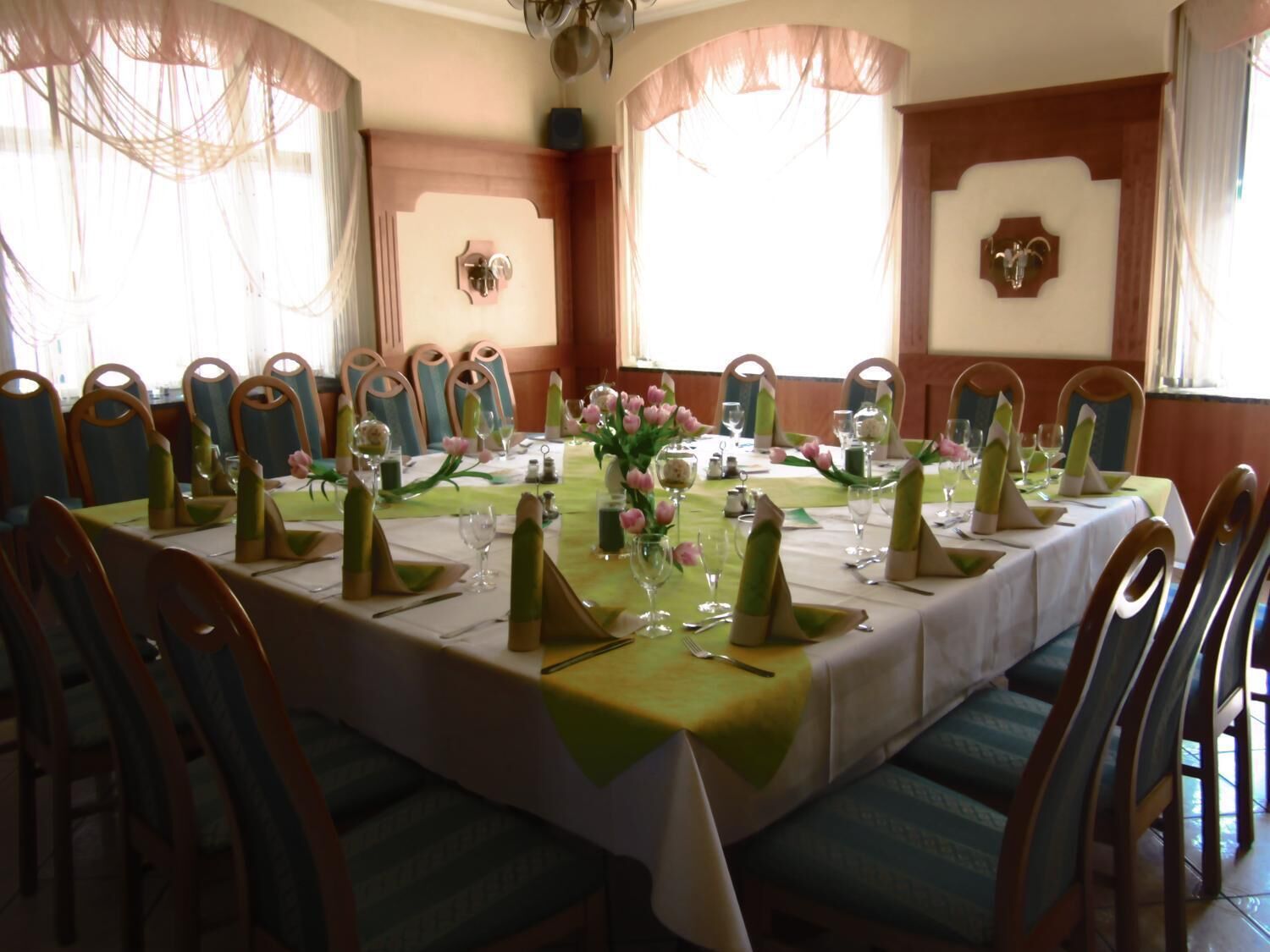Comedor con una larga mesa dispuesta para una comida, rodeada de sillas.