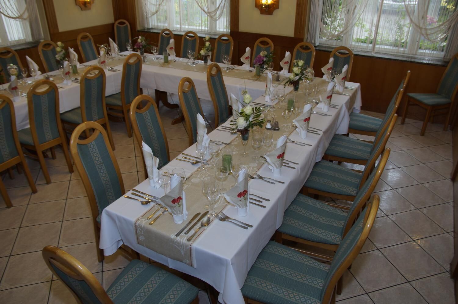 A long dining table set with chairs, each with a white tablecloth and napkin rings.