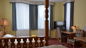 A hotel room with a bed, a desk with a chair, a television, and a lamp.