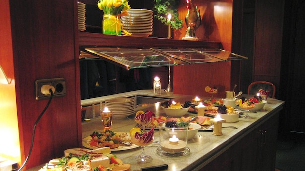 A buffet setup with various dishes, candles, and a decorative centerpiece.