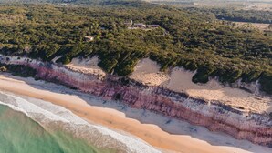 An aerial view of a coastal area with a beach, cliffs, and scattered buildings.