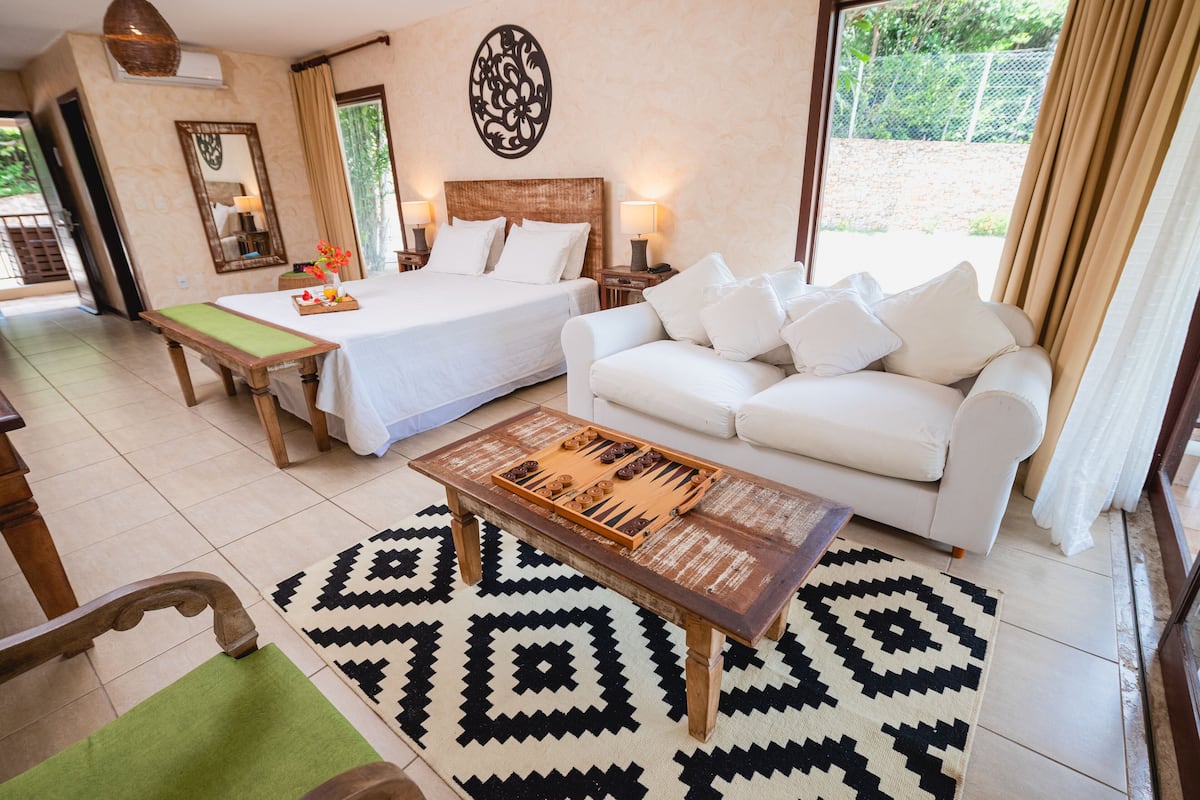 Una habitación de hotel con cama, sofá, mesa de centro y alfombra estampada.