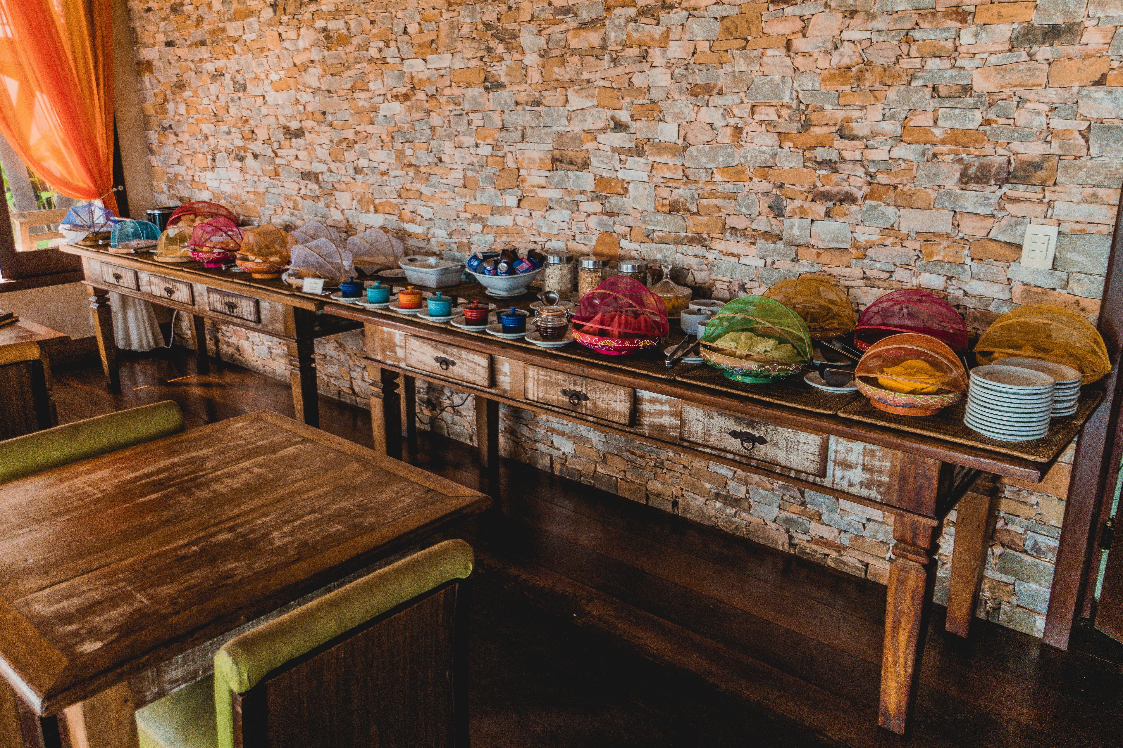 A long wooden table with a stone wall backdrop, filled with various dishes and containers.