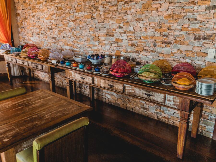 A long wooden table with a stone wall backdrop, filled with various dishes and containers.