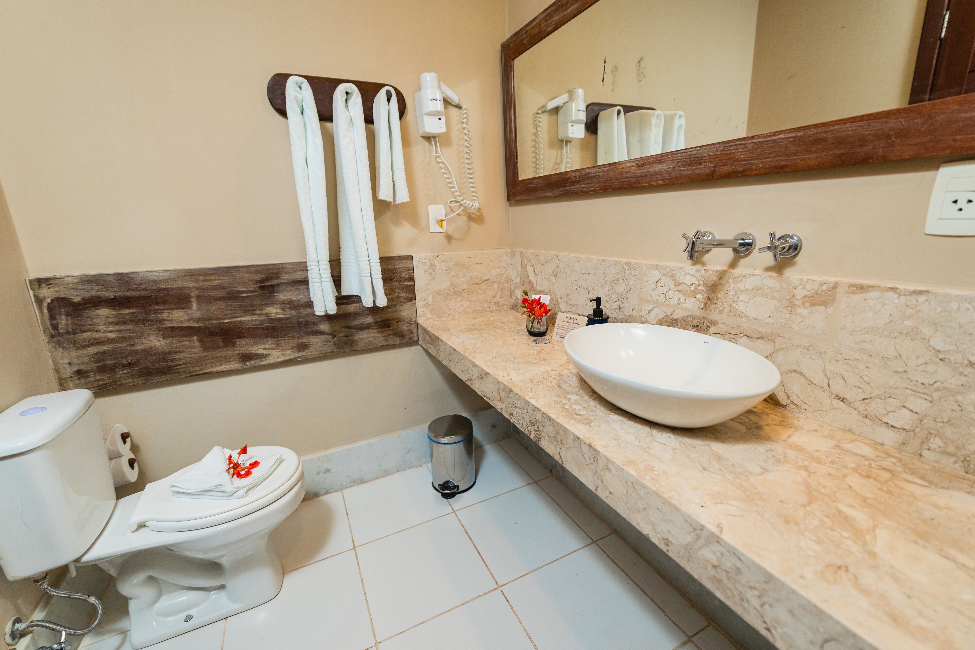 A bathroom with a toilet, a sink, a mirror, and a towel rack.