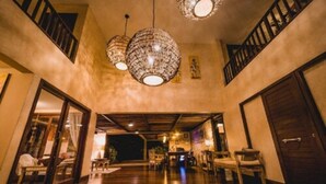 A spacious lobby with a high ceiling, a staircase, and a large wooden table in the center.