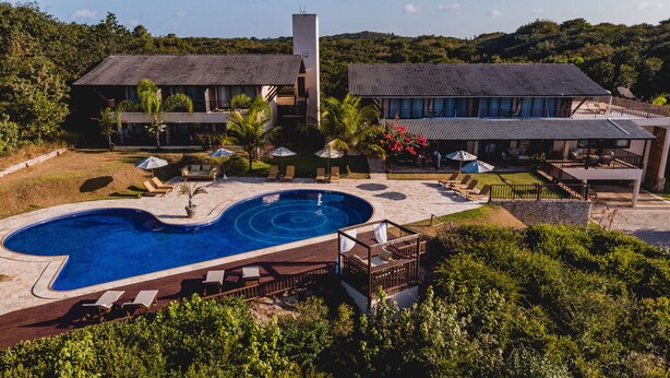 A resort with a swimming pool, lounge chairs, and a covered patio area.