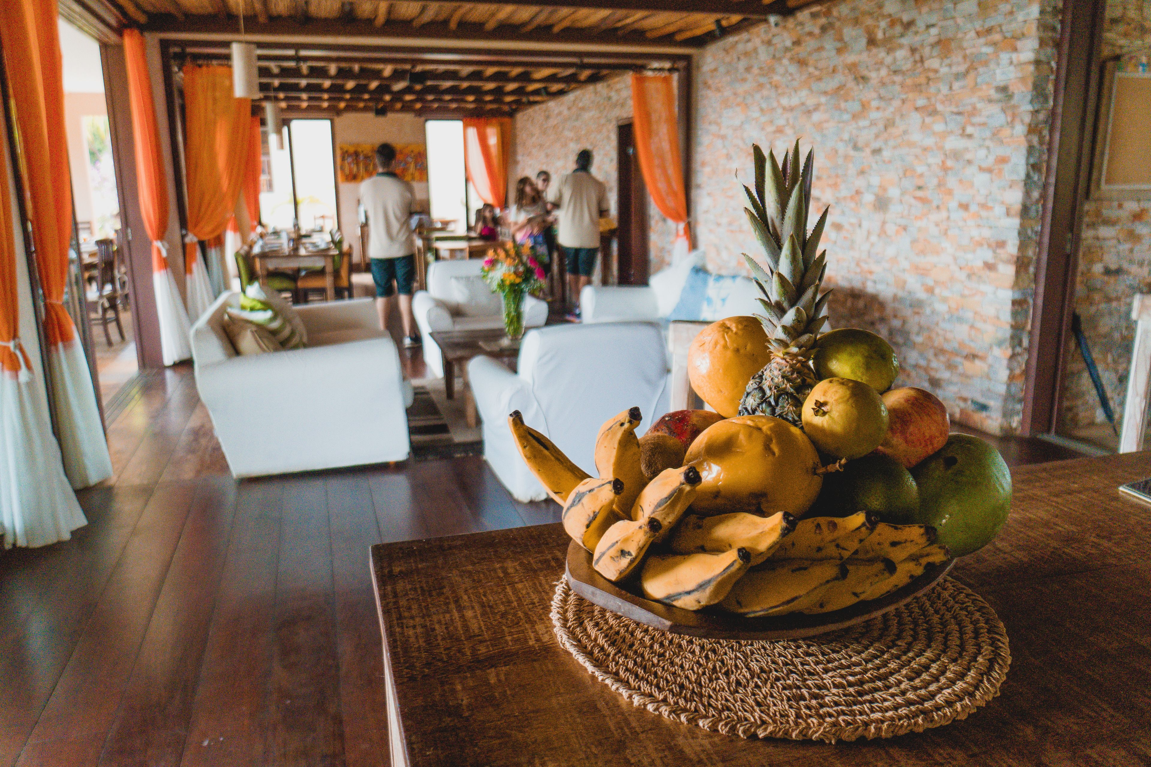 A room with a wooden floor, white furniture, and a fruit bowl on a woven mat.