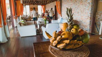 A room with a wooden floor, white furniture, and a fruit bowl on a woven mat.